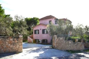 a large pink house with a stone wall at Aegina3views in Kipséli