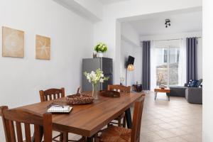 a dining room table with chairs and a living room at Andros Apartments with Free Parking in Steniaí