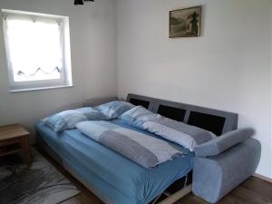 a bed with blue sheets in a room with a window at Ferienhaus Skarbina in Zell-Pfarre