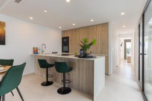 a kitchen with green bar stools and a counter at Serenity Garden & Spa in Los Alcázares