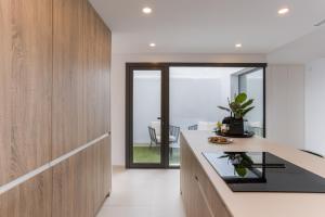 a kitchen with white walls and wooden cabinets and a counter top at Serenity Garden & Spa in Los Alcázares +48 photos