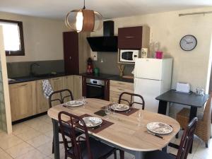 a kitchen with a wooden table with chairs and a white refrigerator at Le relais de la motte in Thuré