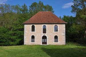a brick building with a brown roof on a field at Le moulin brûlé in Béthines