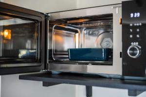 a microwave oven with its door open on a shelf at Sfeervol appartement voor 2 personen De Jonge Blomme in Kamperland