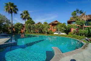 a swimming pool at a resort with palm trees at The Grace Amphawa in Amphawa