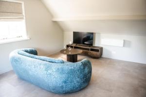 a living room with a blue chair and a table at Sfeervol appartement voor 2 personen De Jonge Blomme in Kamperland