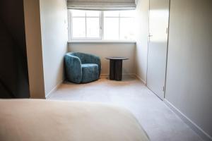 a room with a chair and a table and a window at Sfeervol appartement voor 2 personen De Jonge Blomme in Kamperland