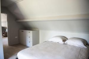 a white bed with two pillows in a bedroom at Sfeervol appartement voor 2 personen De Jonge Blomme in Kamperland +5 photos