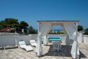 a gazebo with white chairs and a table at Le Gemelle Boutique Hotel in Torre Suda