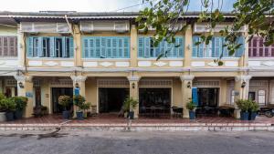 un grande edificio giallo con finestre con persiane blu di The Columns a Kampot
