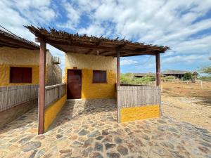 an outside view of a yellow building with a roof at Refugio Pantu in Cabo de la Vela