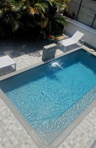 a large swimming pool with two chairs in a yard at Les Caramboles- Appartement Cosy in Sainte-Suzanne