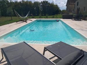 a swimming pool with two chairs and a television in it at Domaine la jarrie in La Bussière