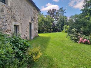 an outside view of a stone house with a yard at Domaine la jarrie in La Bussière
