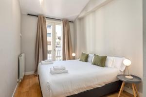 a bedroom with a large white bed with a window at Flateli Nord in Girona