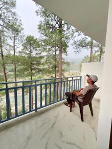 a man sitting in a chair on the balcony of a house at Hotel prayagraj in Barkot