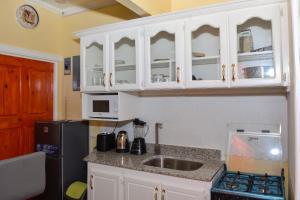 a kitchen with white cabinets and a sink and a refrigerator at Duncan Street Guesthouse in Georgetown +93 photos