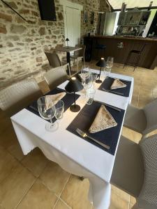 a white table with glasses and a slice of pizza on it at Le Cantou in Affieux