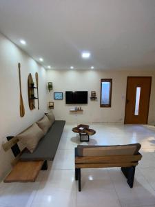 a living room with a couch and a tv at Recanto do Ofurô in Ilhéus
