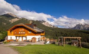 a large wooden house with mountains in the background at Cone da Val in San Vigilio Di Marebbe