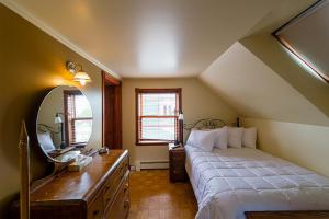 a bedroom with a bed and a desk and a mirror at Auberge Mr James in Rivière-du-Loup