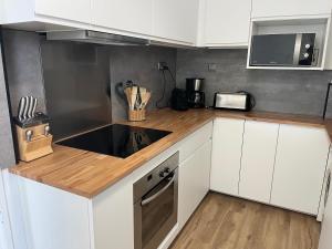 a kitchen with white cabinets and a wooden counter top at Le Face à La Mer in Ajaccio