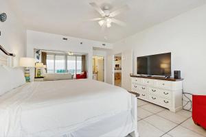 a bedroom with a white bed and a flat screen tv at Navarre Beach Regency 203 in Navarre