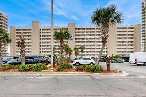 a parking lot with palm trees in front of a large building at Navarre Beach Regency 203 in Navarre