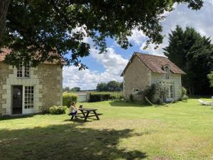 a woman sitting on a picnic table in front of a building at Les forts in Leigné-les-Bois