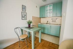 uma cozinha com armários verdes e uma mesa e cadeiras em Apartment Stela em Belgrado