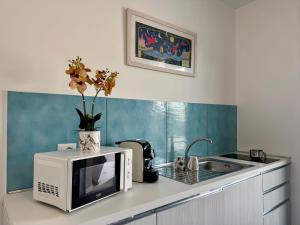 a kitchen with a microwave and a vase with flowers at Aurora View Resort - Boutique Suites in Mascali