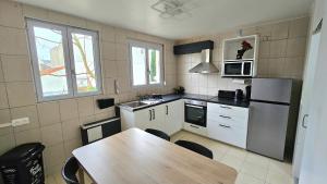a kitchen with a table and a refrigerator and a microwave at Blue Duplex Proche Paris & Stade De France in Drancy