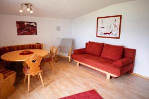 a living room with a red couch and a table at A schön's Platzerl - Apartment Argus in Fügenberg