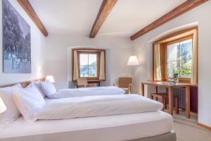 two beds in a room with two windows at Hôtel Bodenhaus in Splügen