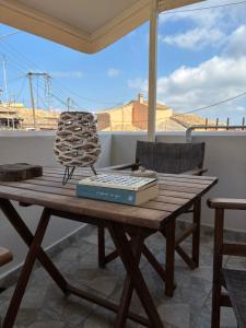 Ein Holztisch mit einem Buch und einem Stuhl auf einer Terrasse in der Unterkunft Laundry House in Sinarádes