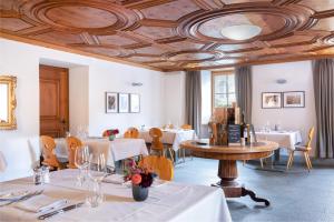 a restaurant with tables and chairs and a coffered ceiling at Hôtel Bodenhaus in Splügen
