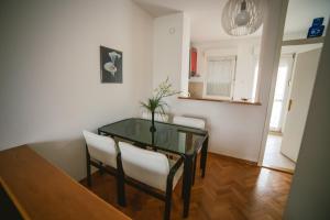 comedor con mesa de cristal y sillas blancas en Viktorija Apartment, en Belgrado