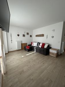 a living room with a black couch and wooden floors at Bormio suite apartment, terme e sci a 5 min. di auto in Valdisotto