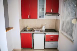 a small kitchen with red cabinets and a sink at Viktorija Apartment in Belgrade +13 photos