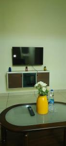 a living room with a television and a vase with flowers on a table at Hangang HOTEL 한강호텔 in Jāmb