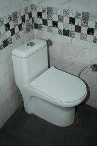 a white toilet in a bathroom with black and white tiles at Hotel the Chandigarh in Chandīgarh