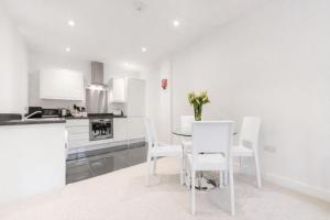 a white kitchen with a table and white chairs at Roomspace Serviced Apartments - Nouvelle House in Sutton