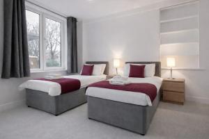 two beds in a room with two windows at Roomspace Serviced Apartments - Nouvelle House in Sutton