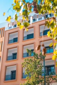 a orange building with windows and a tree at BRĂAT Hôtel in Rabat