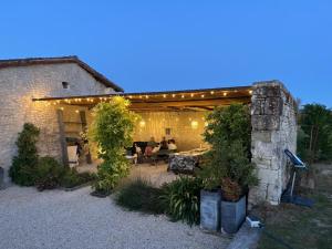 a patio with a group of people sitting under a pergola at Gîte de la petite touche in Seligny