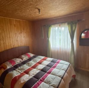 a bedroom with a bed and a window at Cabaña Piola Quilquico in Castro