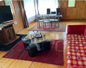 a living room with a table and a red couch at Cabaña Piola Quilquico in Castro