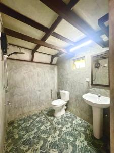 a bathroom with a toilet and a sink at Rainforest cabin in Deniyaya