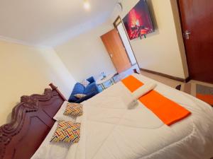 a bedroom with a large white bed with an orange at GREENFIELD STUDlO DONHOLM in Nairobi