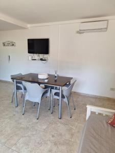 a dining room table with chairs and a tv on the wall at Artigas 505 dpto 2 in Colón